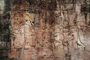 Fototapeta premium Ancient sandstone bas-relief depicting a historical battle and warriors on the walls of Bayon Temple in Angkor Thom, Siem Reap, Cambodia