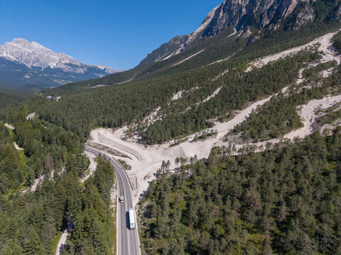 Aerial view of a mountain road passing through a forest with a visible landslide debris flow area in the Dolomites near Cortina d'Ampezzo, Veneto, Italy.