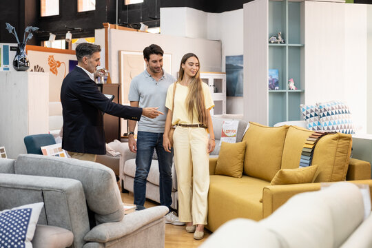 Salesman pointing to a sofa while couple shops for home decor