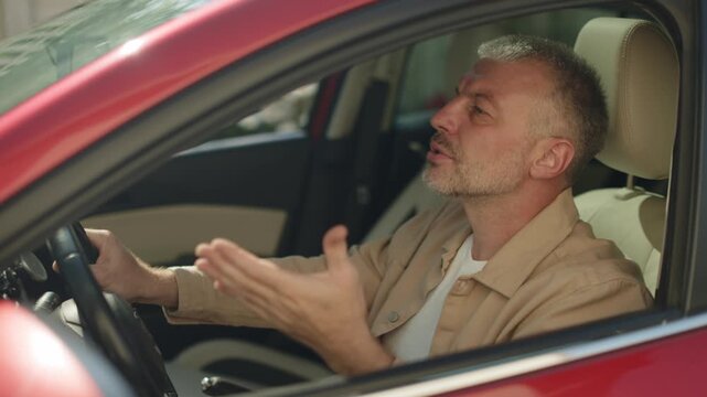 Frustrated man gesturing with hands while driving car, complaining emotionally