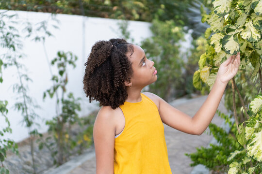 Teenager girl touching green white garden leaves