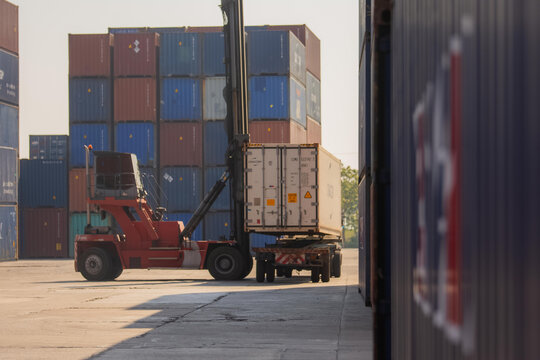 Reach stacker lifting shipping container in industrial terminal with container shipping terminal logistics