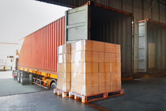 Loading wooden crates onto semi-truck trailer in warehouse bay with warehouse logistics shipping delivery