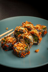 Delicious crunchy sushi rolls with crispy flakes served on blue plate with chopsticks © Ilias