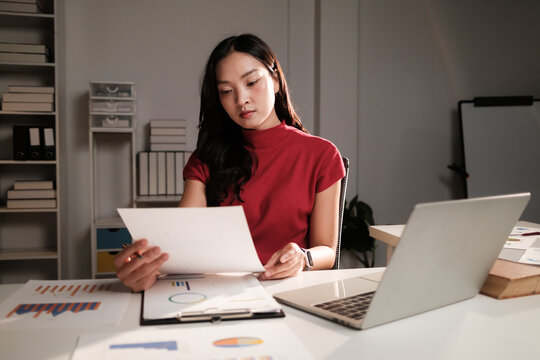 Young woman analyzing financial data working late in office
