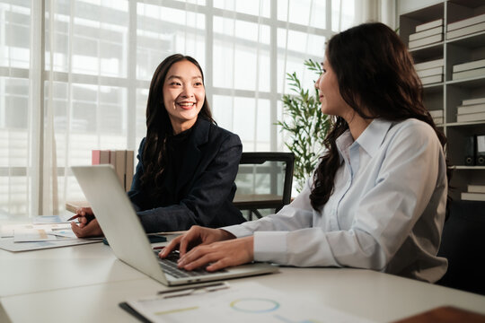 Businesswomen collaborating on laptop in modern office