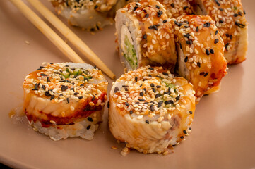 Toasted sesame sushi rolls with sauce drizzle served with wooden chopsticks © Ilias