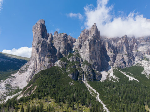 Aerial view of the rugged limestone cliffs of the Civetta massif in the Dolomites, featuring steep rock faces, pine forests, and scree slopes in Taibon Agordino, Veneto, Italy.