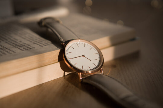 Elegant watch with blank face on open book, time management and education concept mockup