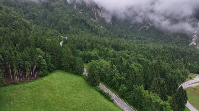 Drone aerial footage flying over alpine road in Slovenia Alps, during cloudy summer day with scenic peaceful mountains forest and natural calm atmosphere of travel