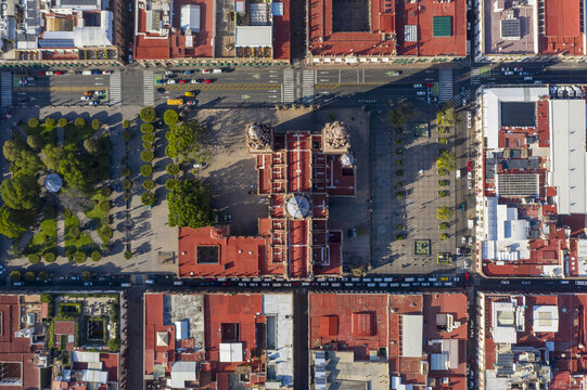 Aerial view of Catedral de Morelia surrounded by historic red-tiled rooftops, urban streets, and green plaza spaces in Morelia, Michoacan, Mexico.