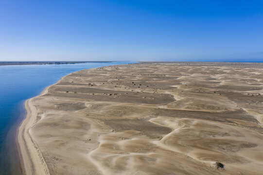 Aerial view of the vast sand dunes of Magdalena Bay meeting the blue waters of the Pacific Ocean in Puerto Adolfo Lopez Mateos, Baja California Sur, Mexico.