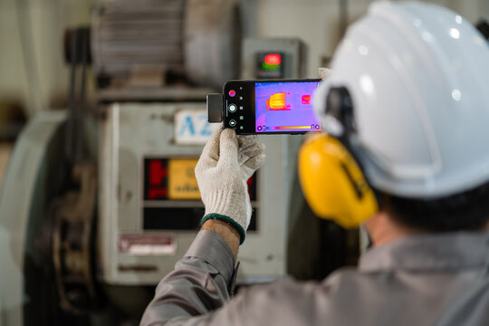Factory technician using a clip on thermal imaging module attached to a smartphone to inspect an electric motor