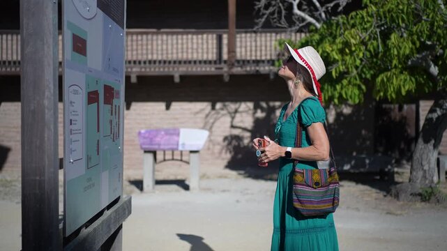 Mature woman walks through Casa Grande in Sonoma, reading about the historic site of General Vallejo on a sunny morning.