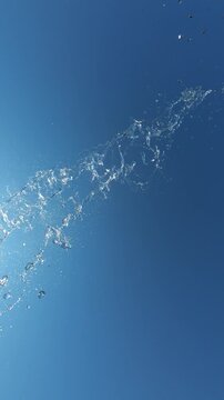 Water Splash Spraying Towards Camera Against Blue Clear Sky in Slow Motion