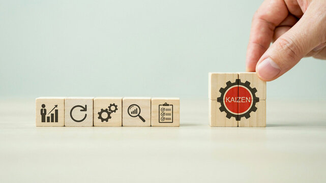 Hand placing kaizen block with business icons for continuous improvement process and efficiency management strategy