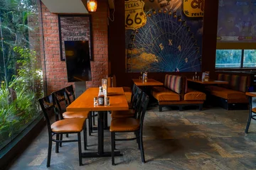 Fotobehang Horeca Spacious casual dining restaurant interior with wooden tables, brick walls, and decorative Texas themed wall art, perfect for hospitality and food industry marketing concepts.  © Takeshwar