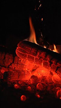 Glowing red embers pulsing in dying campfire at night
