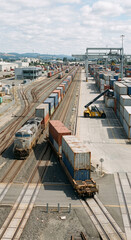 Naklejka premium High vertical view of a long intermodal freight train in a large rail terminal surrounded by shipping containers and logistics infrastructure