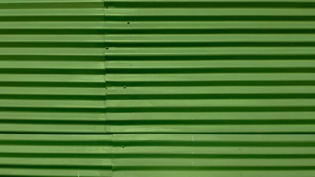 Green corrugated metal sheet surface creating a textured industrial background