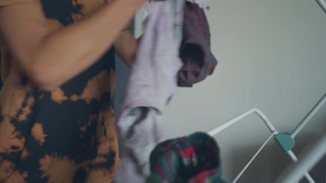 Close-up of arms draping plaid clothing over a folding drying rack