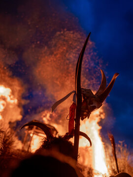 Horned Bus&oacute; costume silhouetted against a ceremonial bonfire