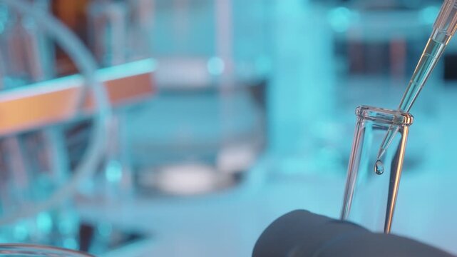 Micropipette dropping blue liquid into test tube in laboratory