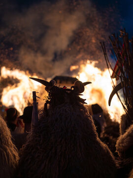 Rear view of a horned Bus&oacute; costume facing a blazing bonfire
