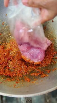Cooking Thai food video showing process of stir frying minced fish paste in wok. Cooking red curry paste with scraped fish meat, adding seasonings, shredded kaffir lime leaves, and fresh chili.