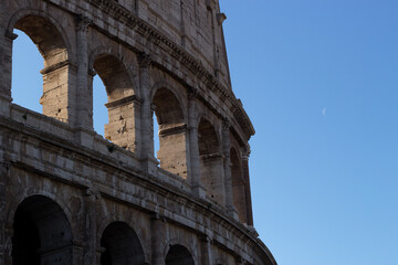 Obraz premium Side View Detail of Roman Colosseum Arches with Crescent Moon in Blue Sky