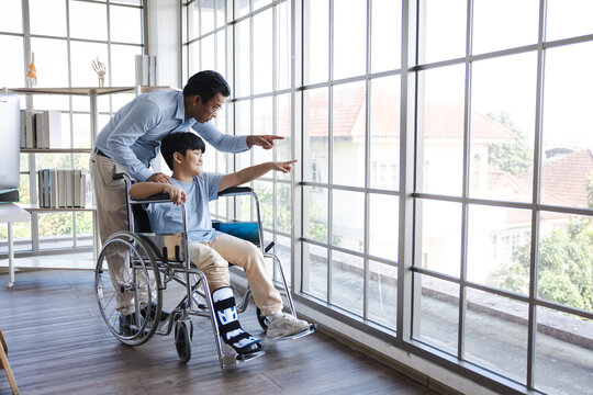 orthopedic walking, Crutches Walks Confidently. Child Step in Rehabilitation with Leg Brace. Asian father helping to support his son, who has a broken ankle