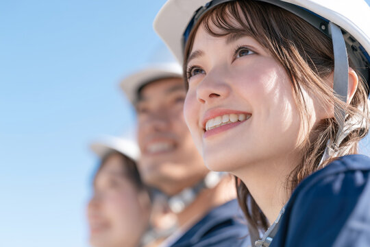 明るい表情で目標を見つめる若い女性作業員と仲間たち