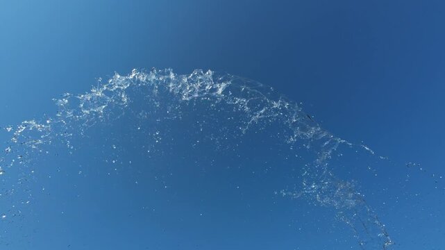 Arc of Water Splashing Upwards Against Clear Blue Sky in Slow Motion