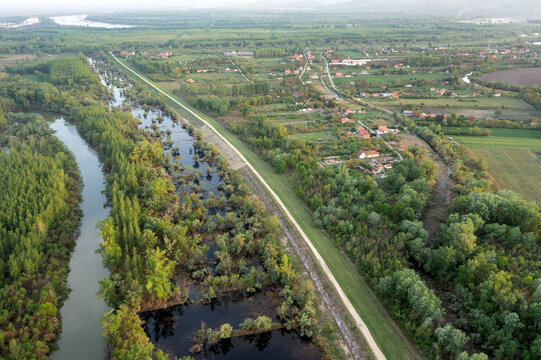 Aerial view of the Tamis River flowing beside its former river channel, now an oxbow lake, with wetlands, agricultural fields, and the Danube visible on the horizon near Jabuka, Vojvodina, Serbia.