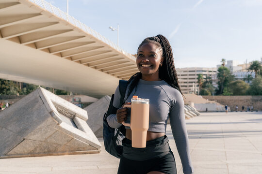 Woman Walking With Water Bottle Near Bridge in Urban Area
