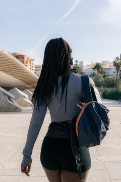 Sporty woman walking with backpack after training in park