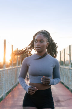 Runner on a Bridge at Sunset With Braids Moving in the Wind