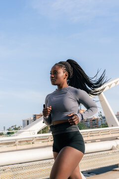 Woman Runs on a Bridge Under Blue Sky During Day