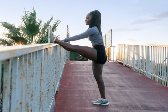 Woman Stretching on a Bridge During Sunset 