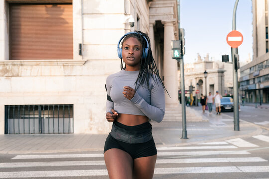 Running Woman in City Street With Headphones During the Day