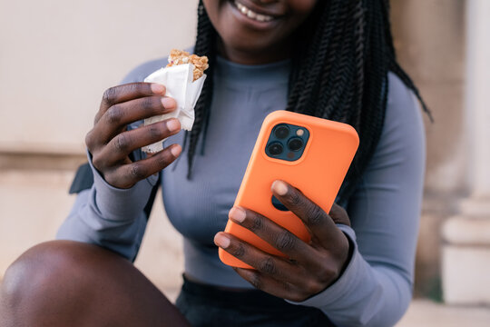 Eating protein bar and using smartphone 