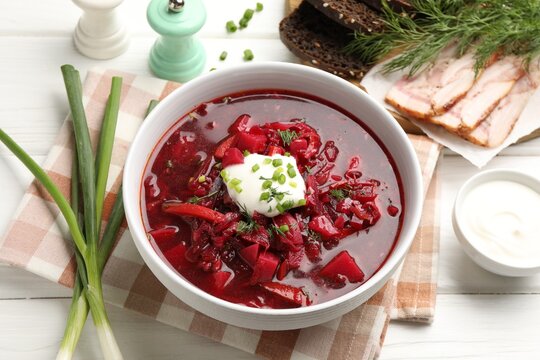 Delicious borscht served on white wooden table, closeup