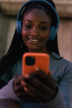 Woman Listens to Music While Looking at Her Phone Outside
