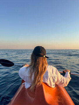 Woman kayaking on a calm sea at sunset