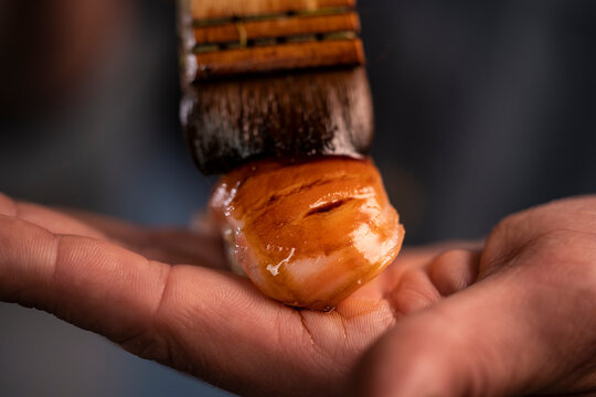 Chef hand glazing nigiri sushi with soy sauce brush