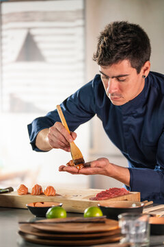 Professional chef preparing salmon nigiri with soy sauce