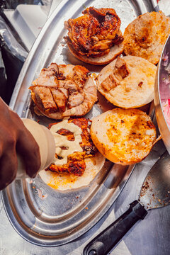 Chef squeezing sauce onto open pork brioche buns