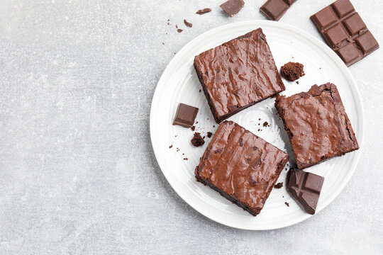 Pieces of tasty brownie on light grey table, flat lay. Space for text