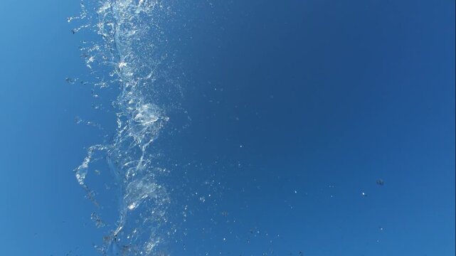 Clear Water Stream Flowing Vertically Against Sunlit Blue Sky