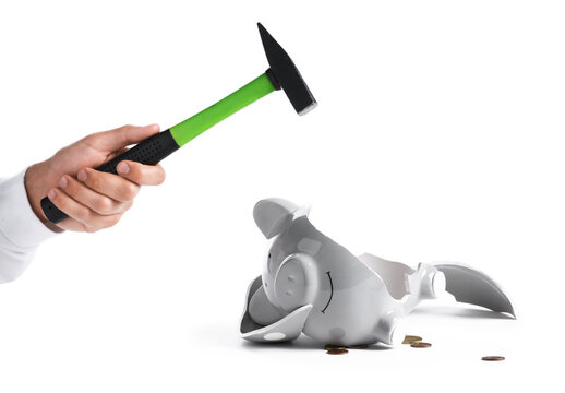 Man breaking piggy bank with hammer on white background, closeup